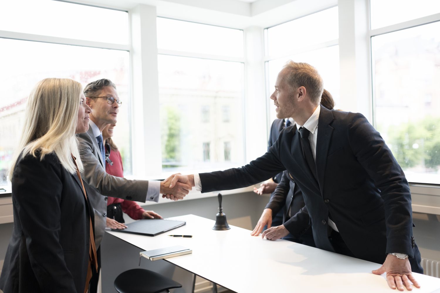 Institutional investors shake hands across a meeting table after the success of agreeing on a spot secondary trade.