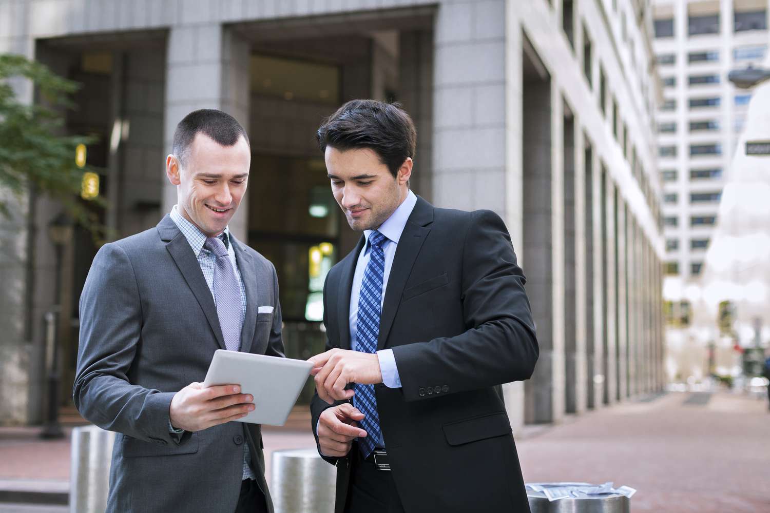 Two stockbrokers look at an amended proxy statement for a company they follow on a pad computer.