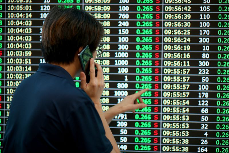 Stock trader talking on cellphone while monitoring stock prices.