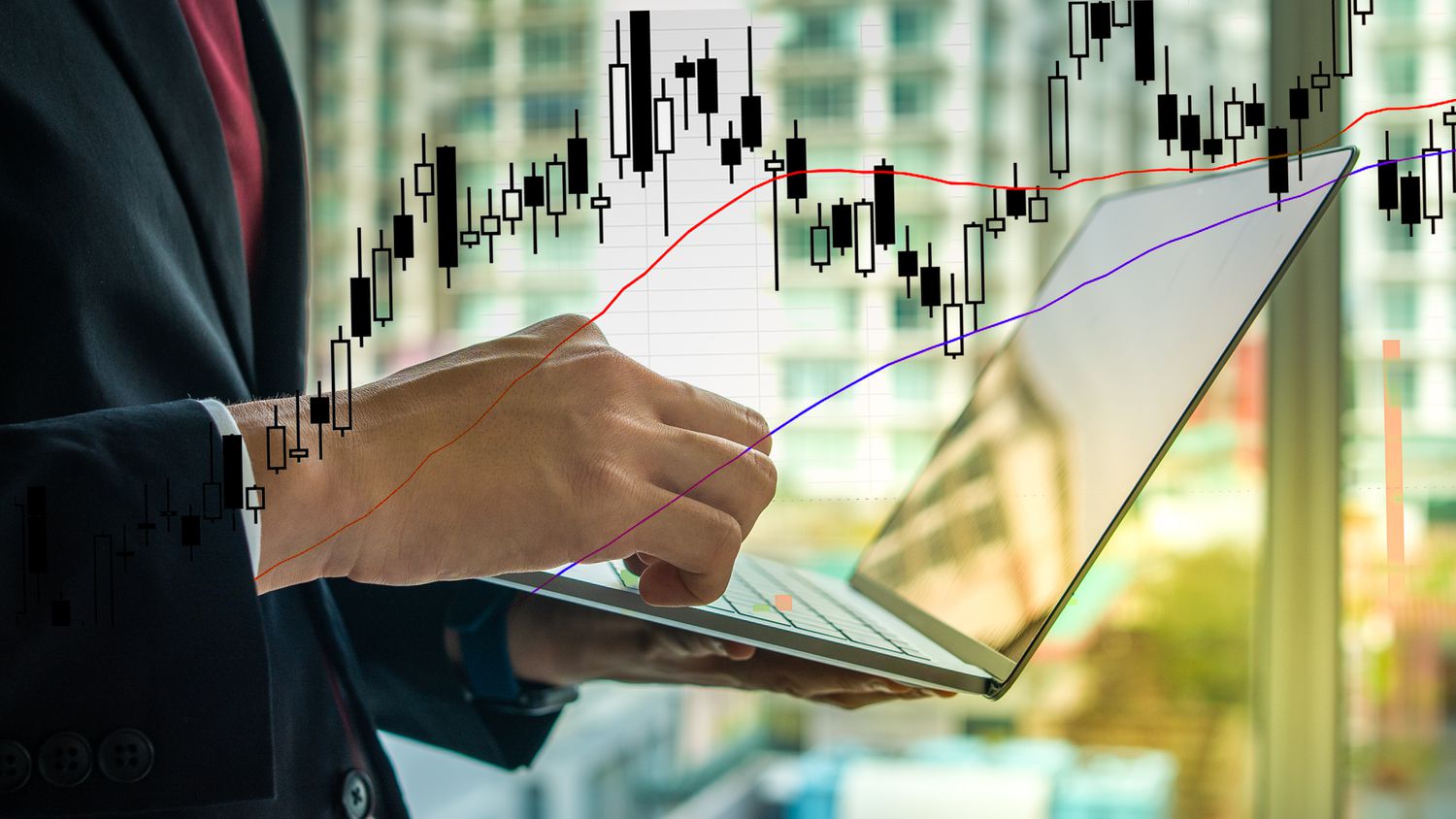 A candlestick chart showing price movement superimposed over a trader making trades on their laptop.