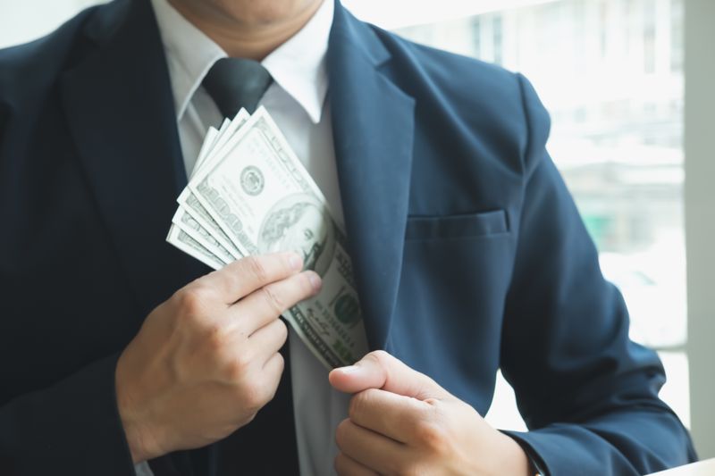 Midsection Of Businessman Putting Money Into Pocket