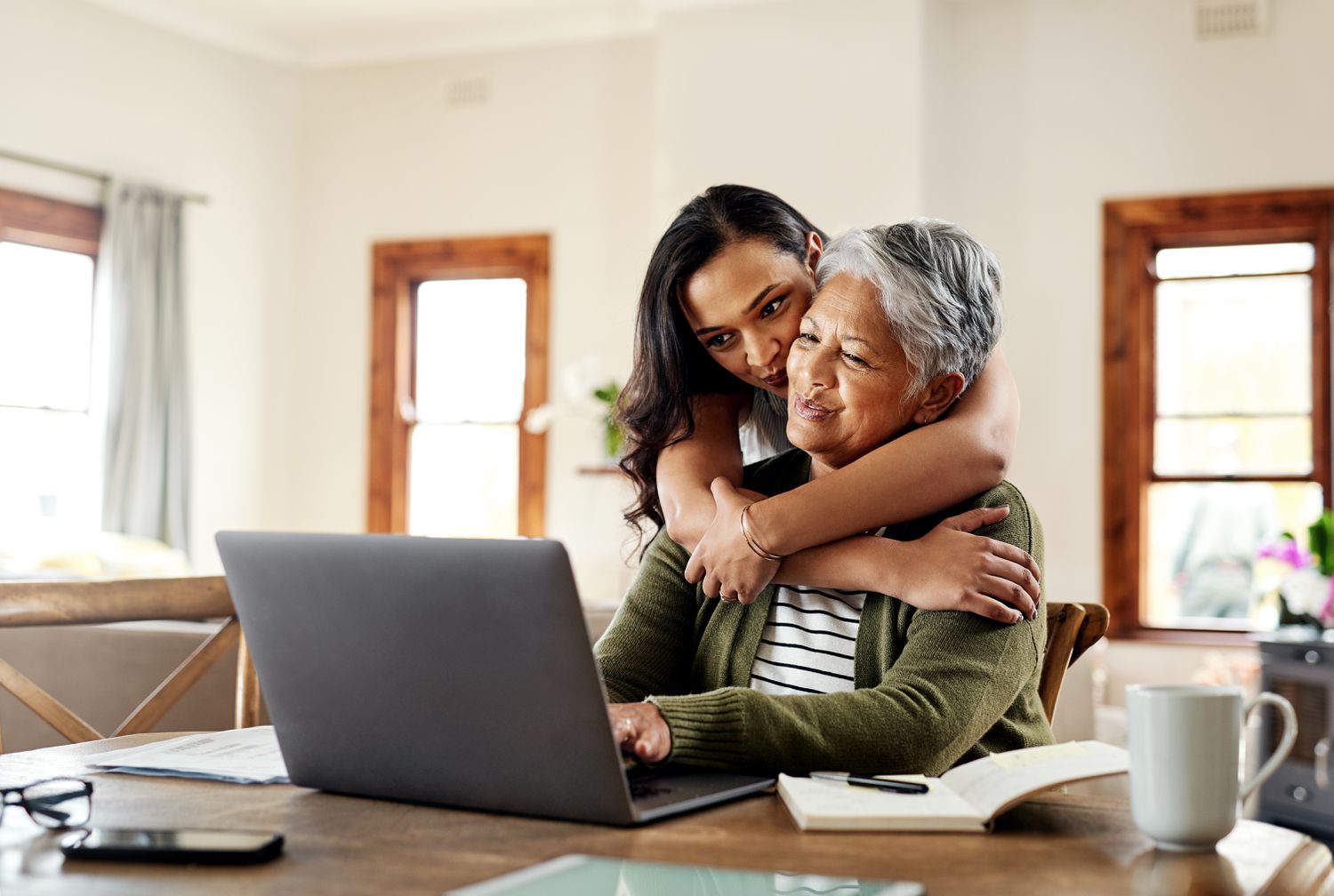 Cropped shot of a young person hugging her grandmother before helping her with her finances on a laptop