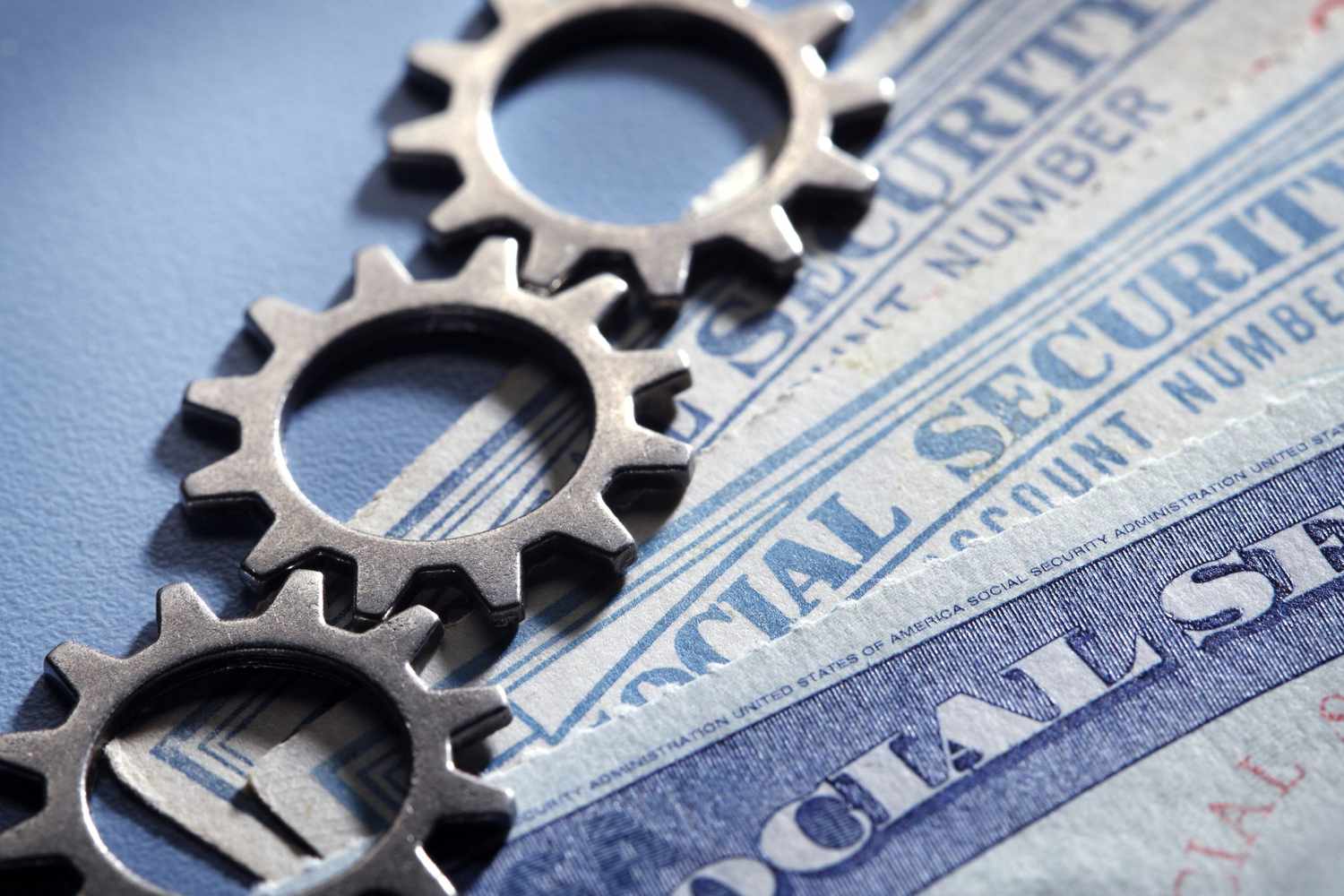 Gears rest on top of a stack of social security cards.