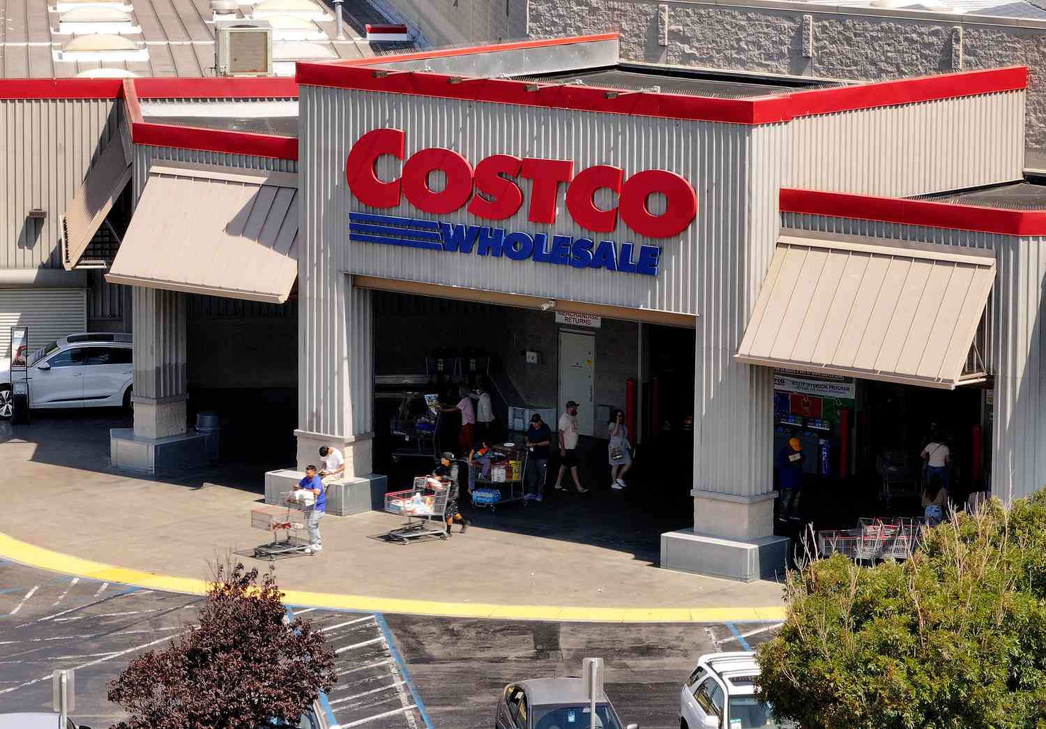 An aerial view of a Costco store, showing the Costco logo and customers exiting the building with shopping carts.