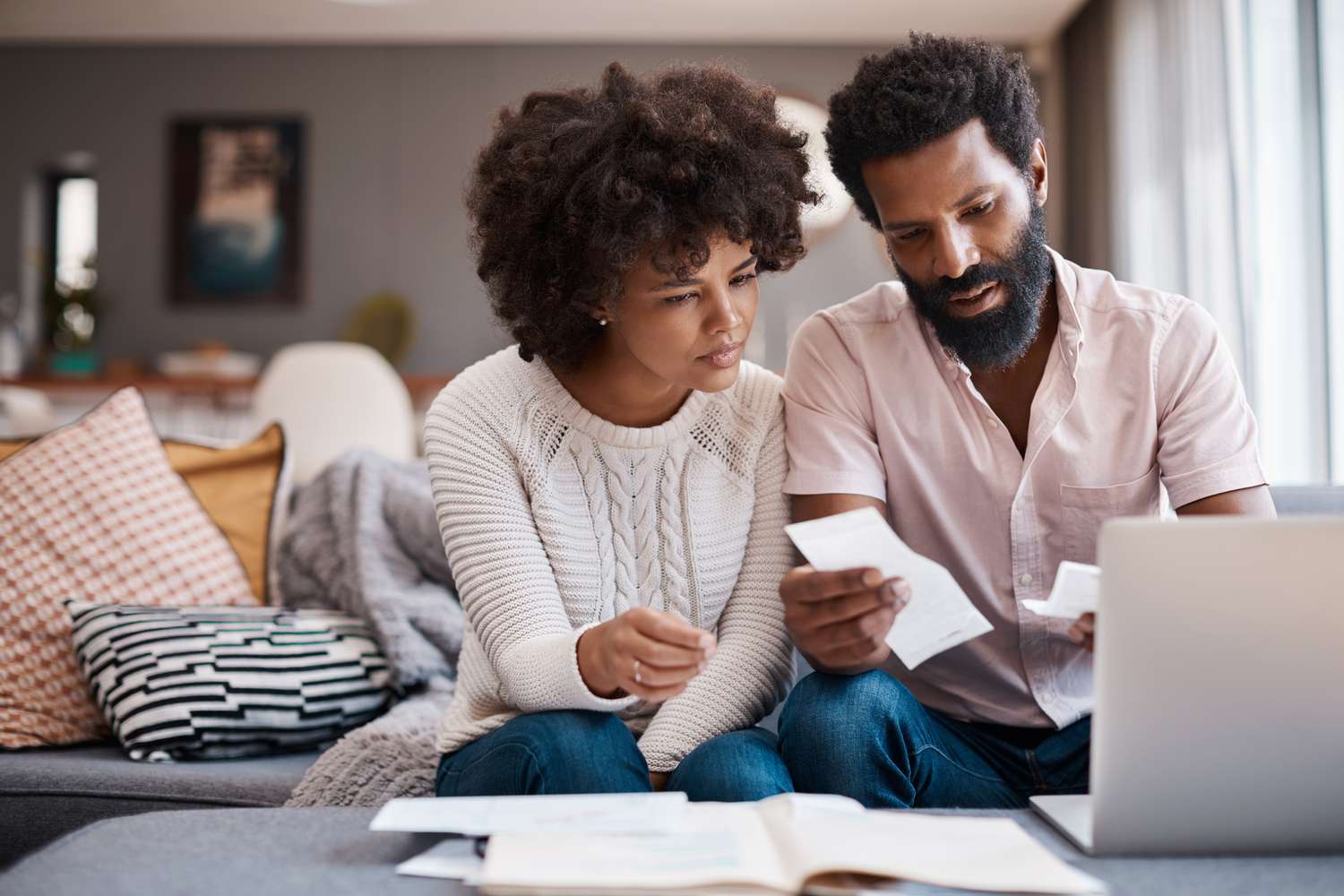 Couple looking at receipts and computer in living room