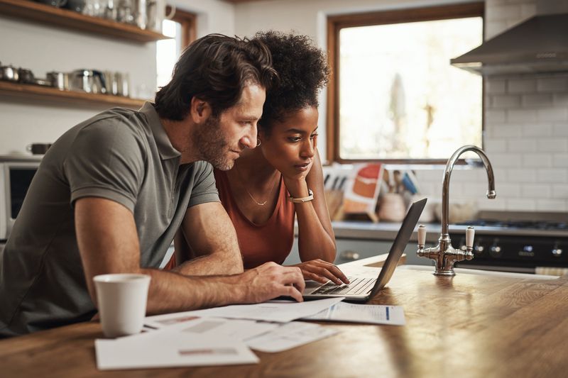 Young couple going through paperwork at home on kitchen counter
