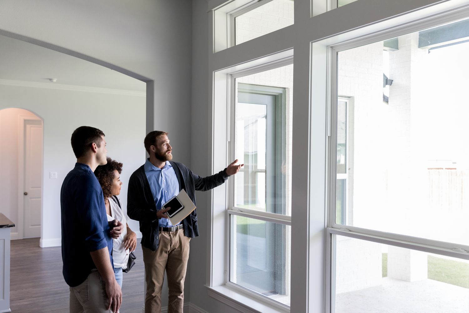 A man and a woman walk through an empty house with a real estate agent