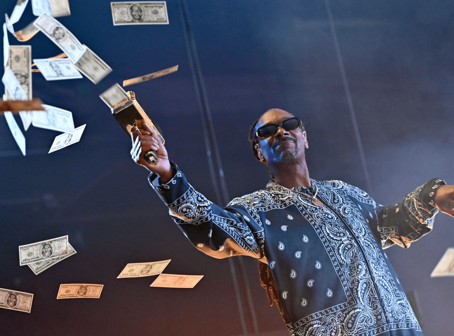 Snooop Dogg shoots from a "cash gun" on stage while performing.