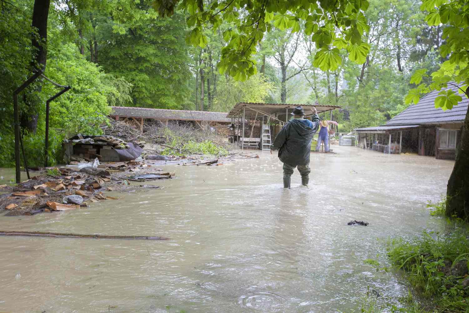 Desperate man standing in front of house in flood after a storm.