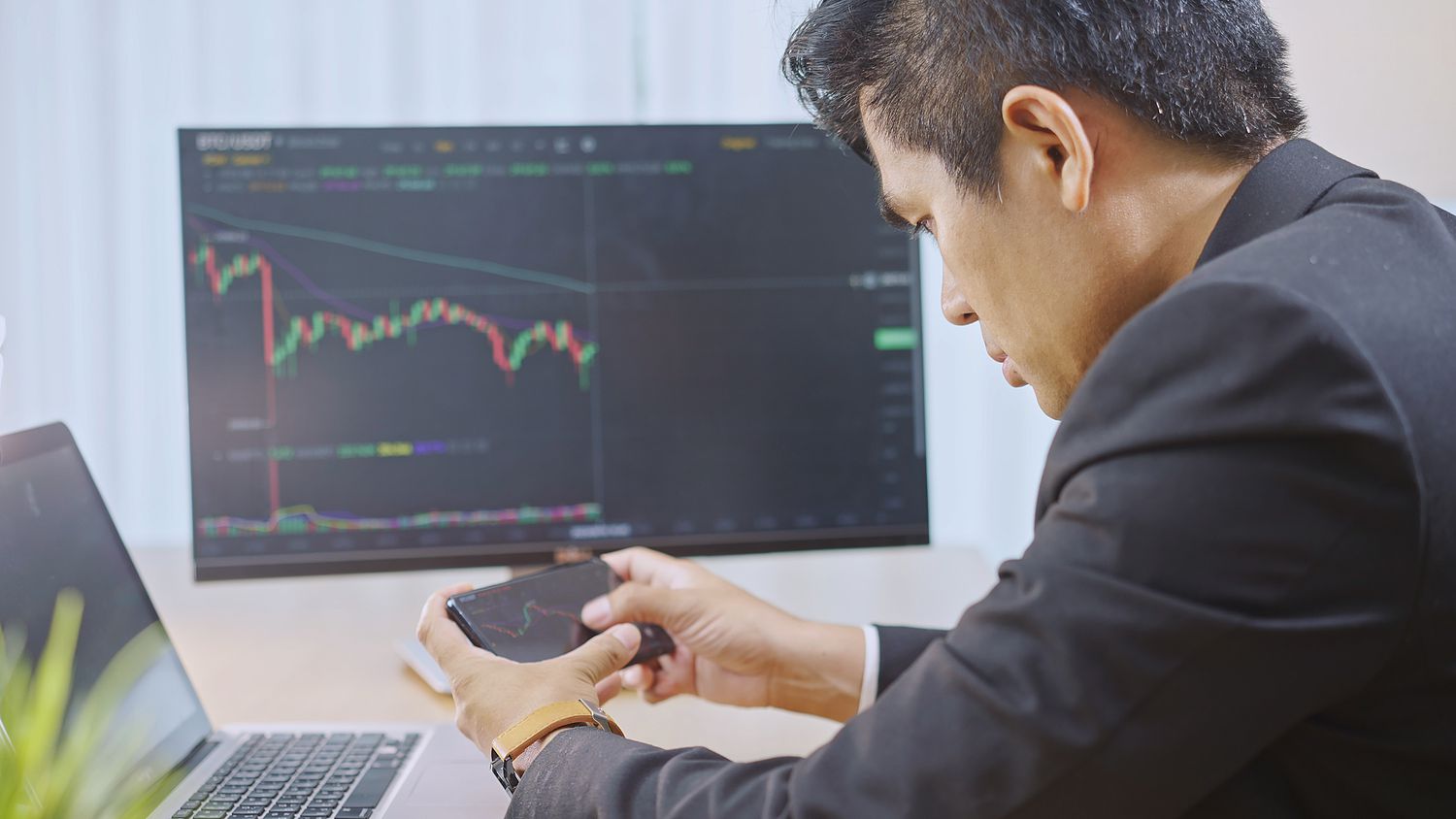 Trader used a phone, laptop, and computer monitor to watch market signals in preparation to place an order.