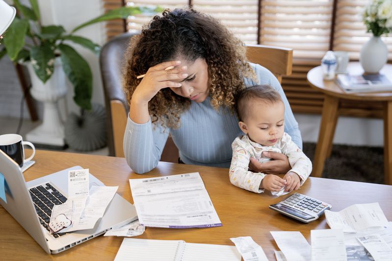 Worried mom holding the child while thinking about how to get enough money to pay missed mortgage payments to prevent foreclosure.
