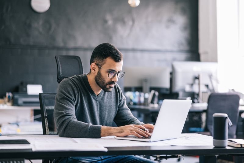 A man works on a laptop in an office.