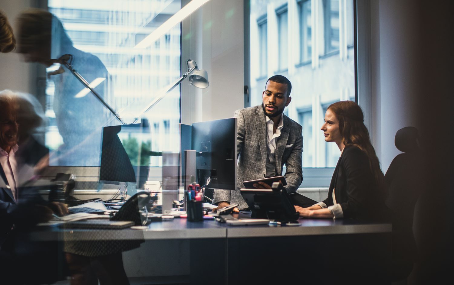 Two colleagues at an underwriting firm review information on a computer screen to determine how much risk an new initial public offering (IPO) will pose.