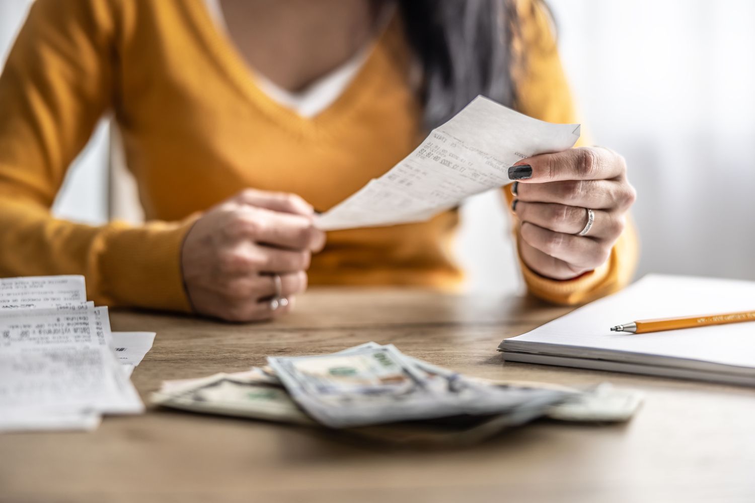 A woman at a table with receipts and dollar bills