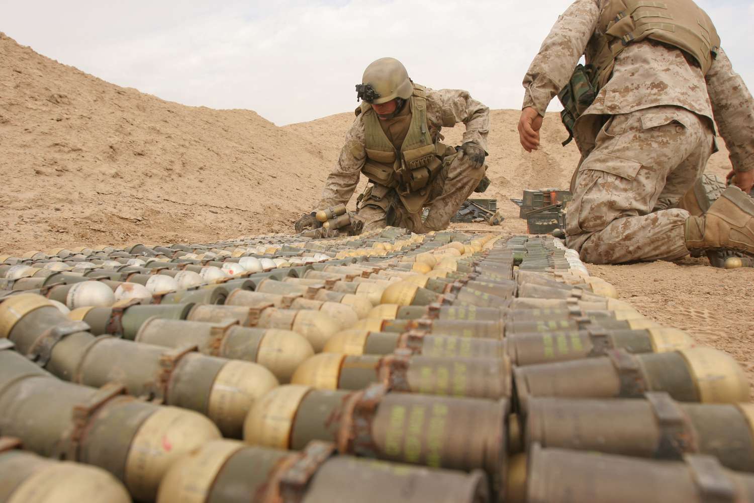 U.S. Marine Corps and U.S. Army explosive ordnance disposal technicians arrange unexploded ordnance for demolition