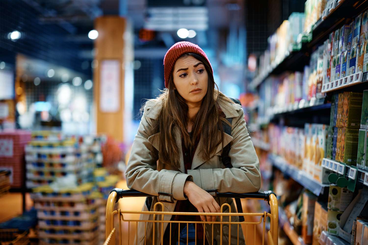 A young adult pushes an empty shopping cart worried about rising prices at the supermarket.