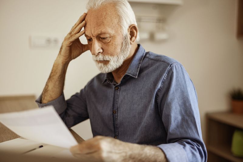Person with gray hair and a beard looking at paperwork