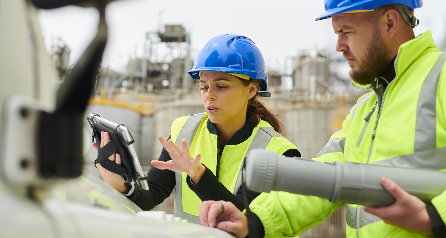 Engineers wearing hardhats at construction site discuss changes to building plans for a financed-funded project.