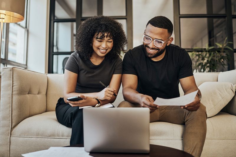 A young couple use their laptop to reserach the pros and cons of a life insurance loan.