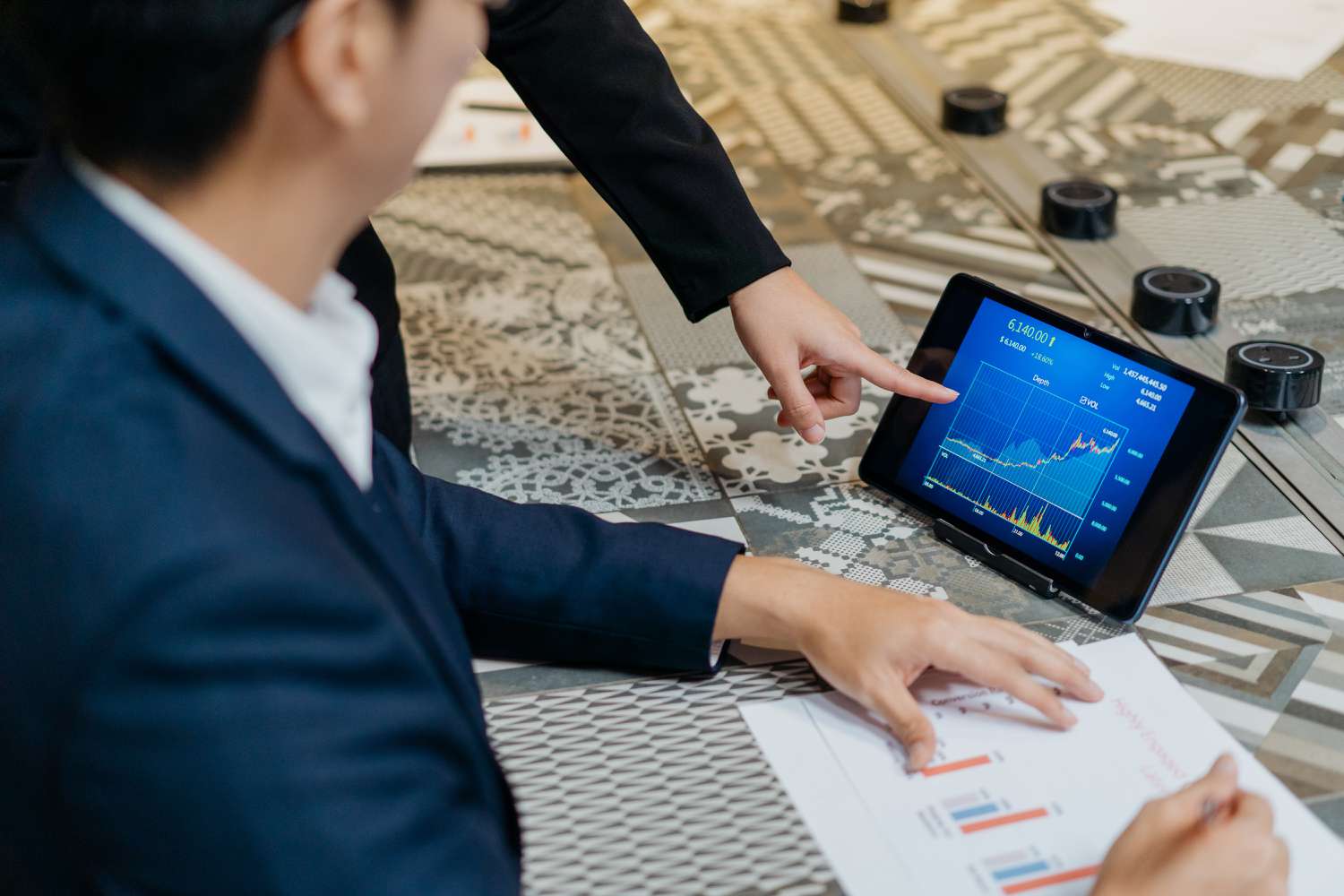 Two business men checking stock market chart on digital tablet
