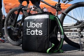 An Uber Eats delivery bag sits on the ground in front of a black bicycle