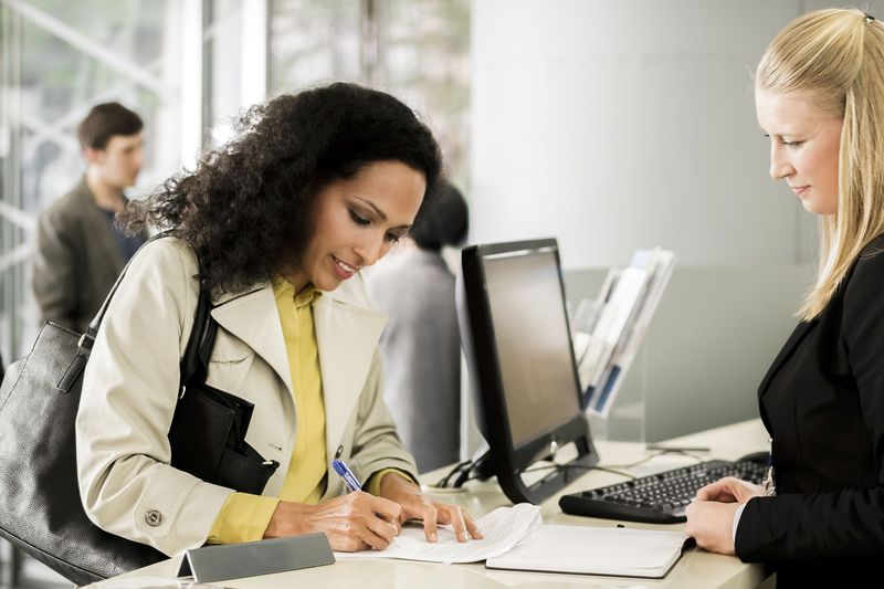 Customer signing a document at the window of a bank teller