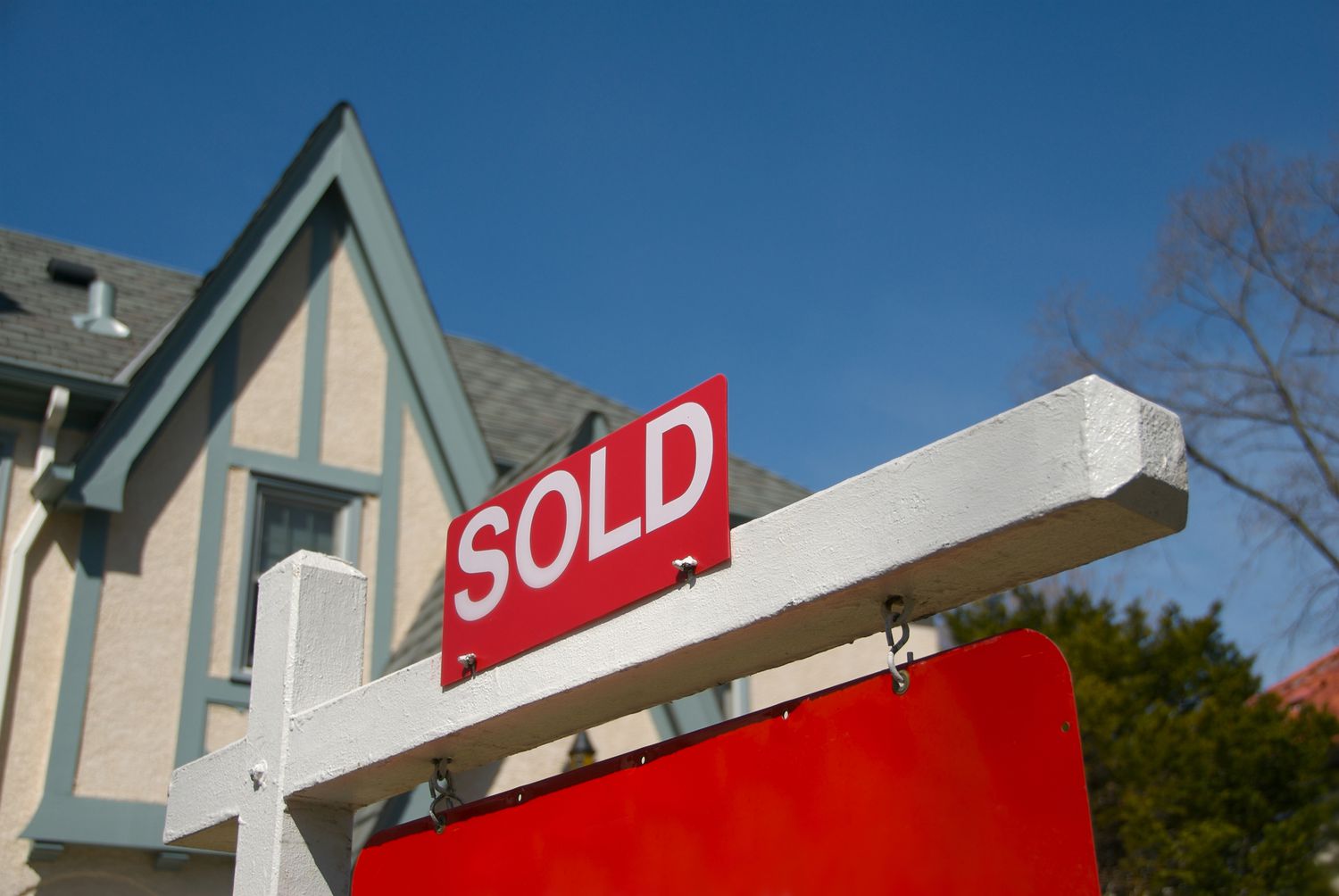 A sold sign in front of house signifying a transfer in ownership