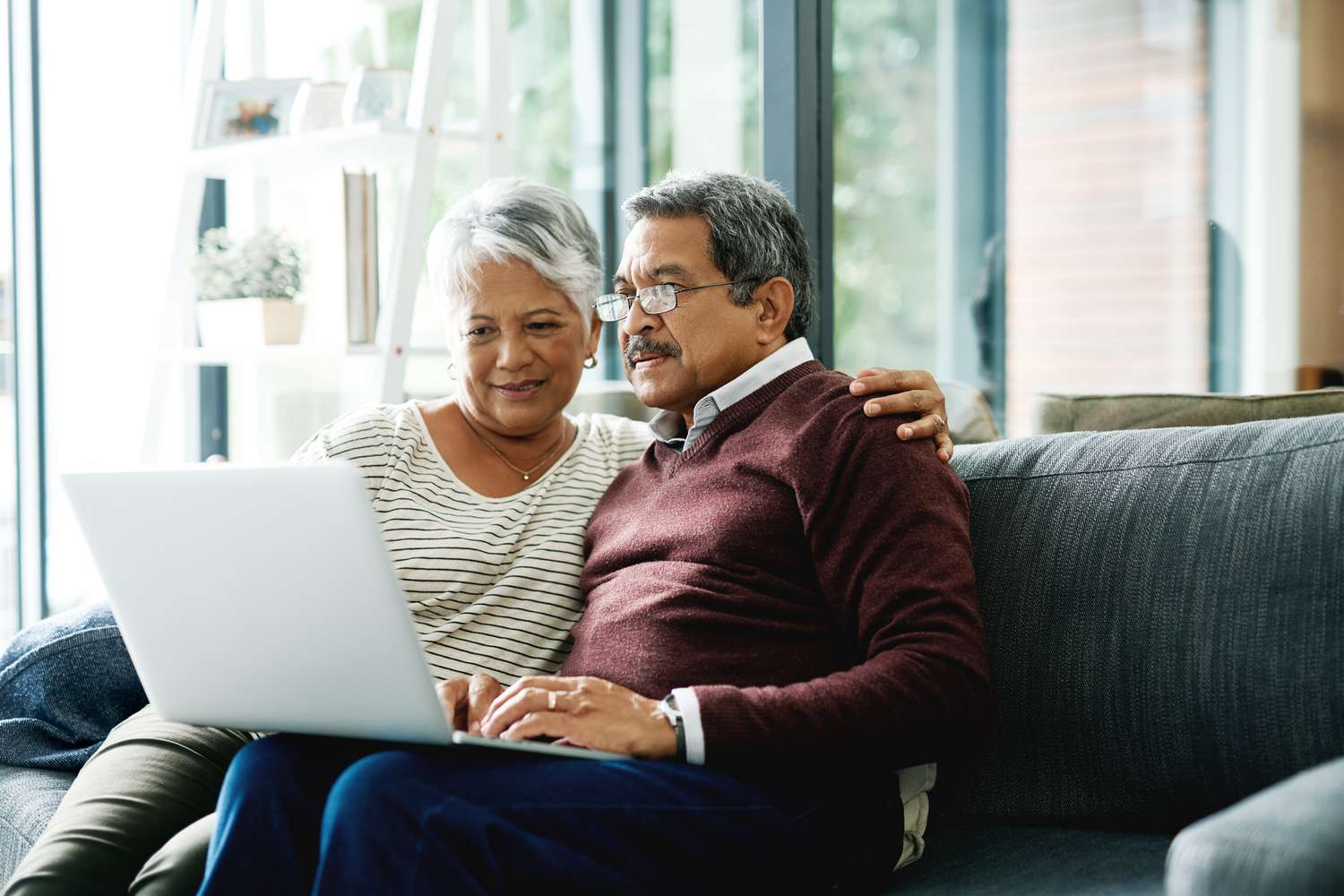 Older couple using laptop at home on couch