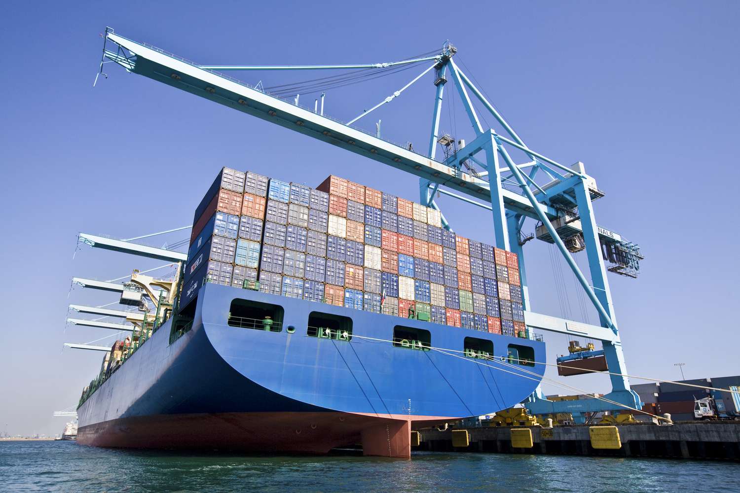 A cargo ship at a dock with cranes loading cargo