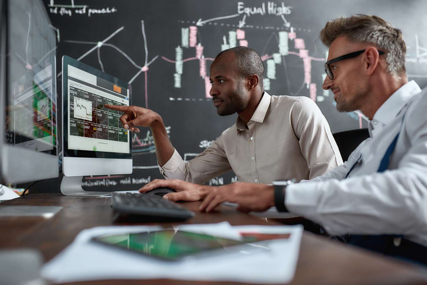 Stock traders looking at different indexes shown on the computer screen to decide which market to invest in.