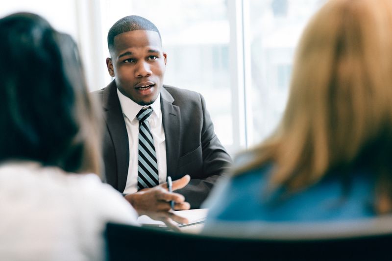 financial advisor speaking to two people whose back of heads can only be seen