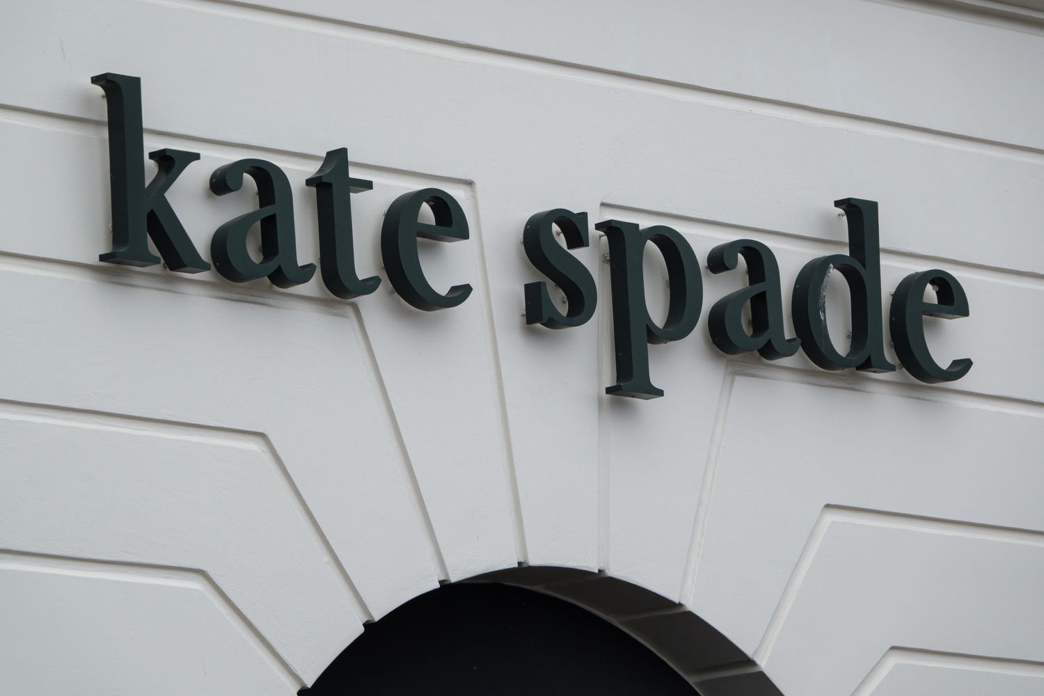 The black Kate Spade logo is seen on the side of a white building.