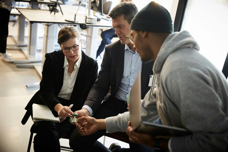Two investors look at a toy in an office with the inventor/entrepreneur whom they’re considering financing.