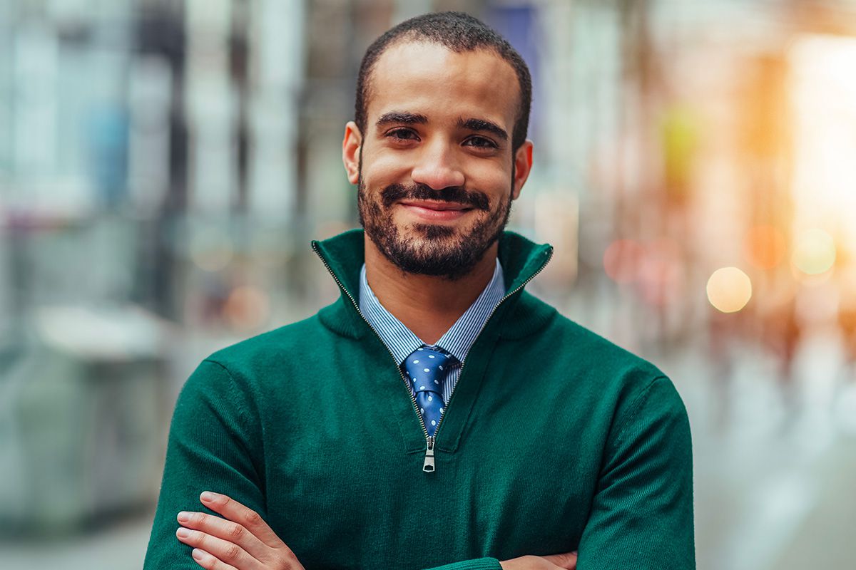 Young man outside with arms crossed and smiling