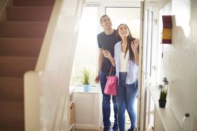 House-hunting couple standing in the hallway of house with a stairway going up
