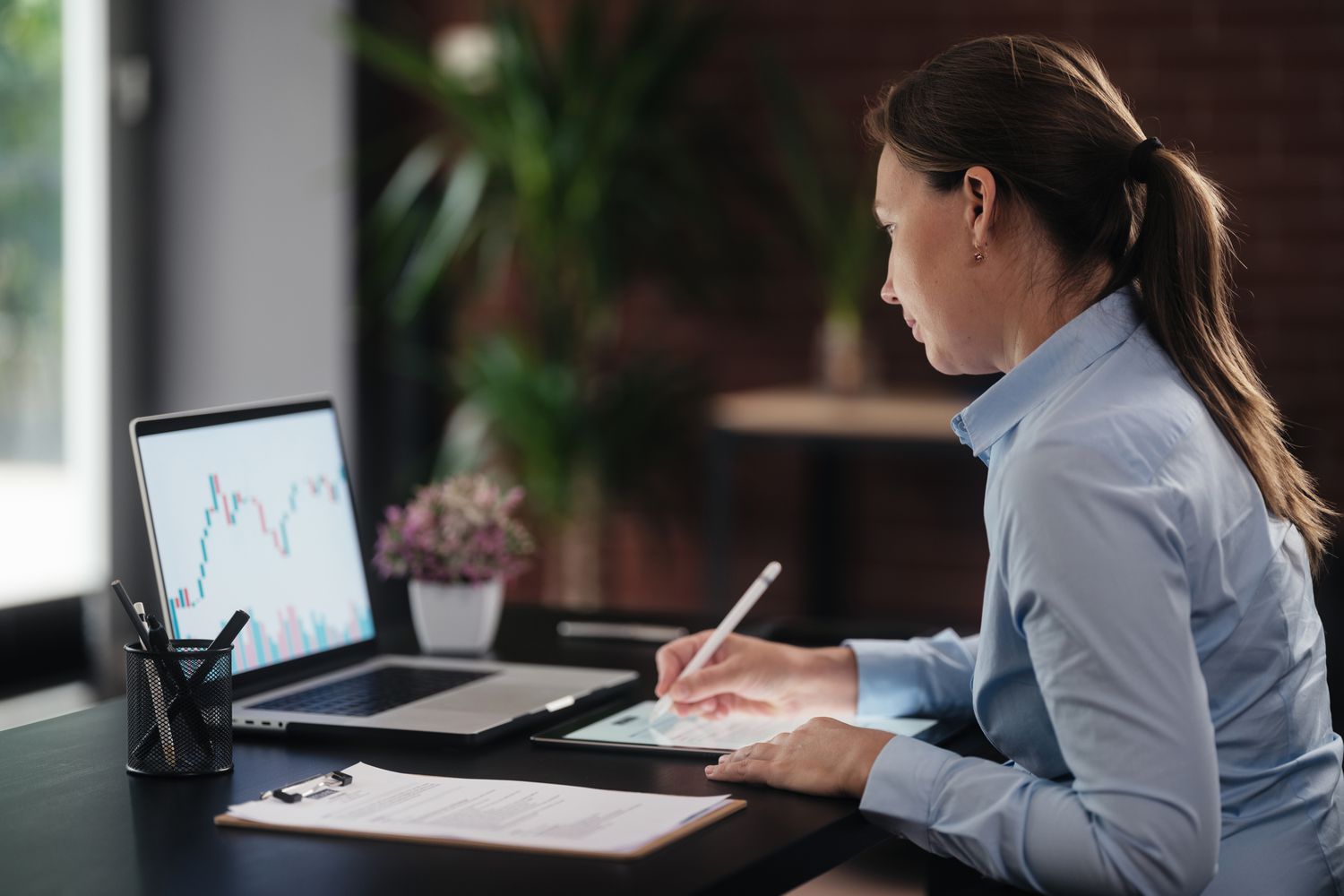 An investor uses a laptop and writes notes to devise a strategy for synthetic dividends on their portfolio holdings.