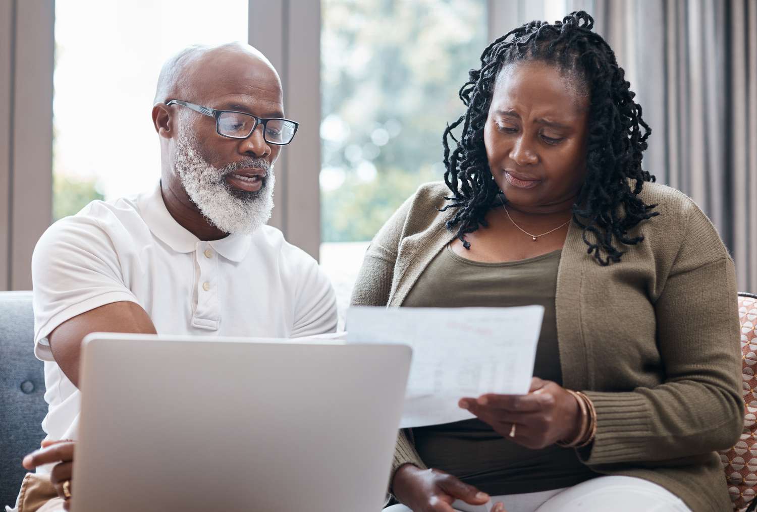 Older couple sitting at home and looking at mortgage documents and a laptop together