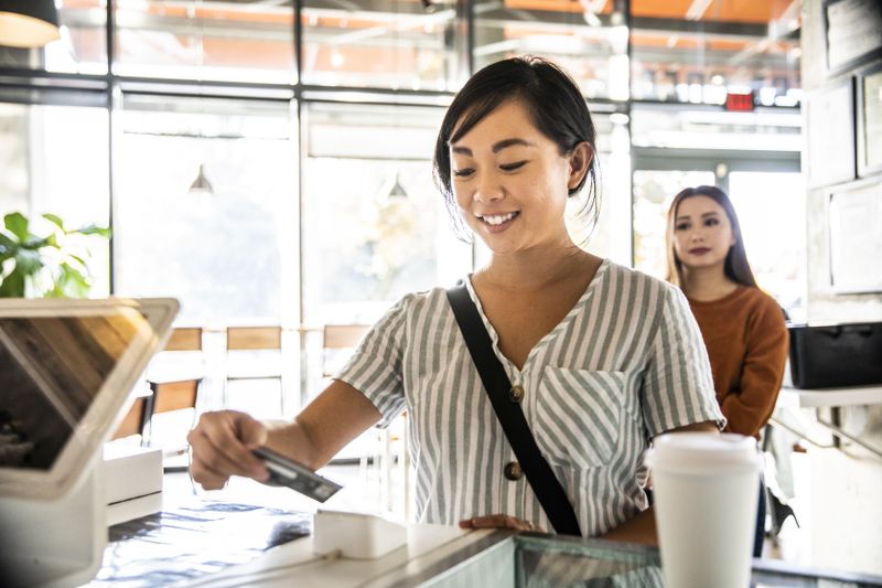 Woman using a credit card reader at a coffee shop counter