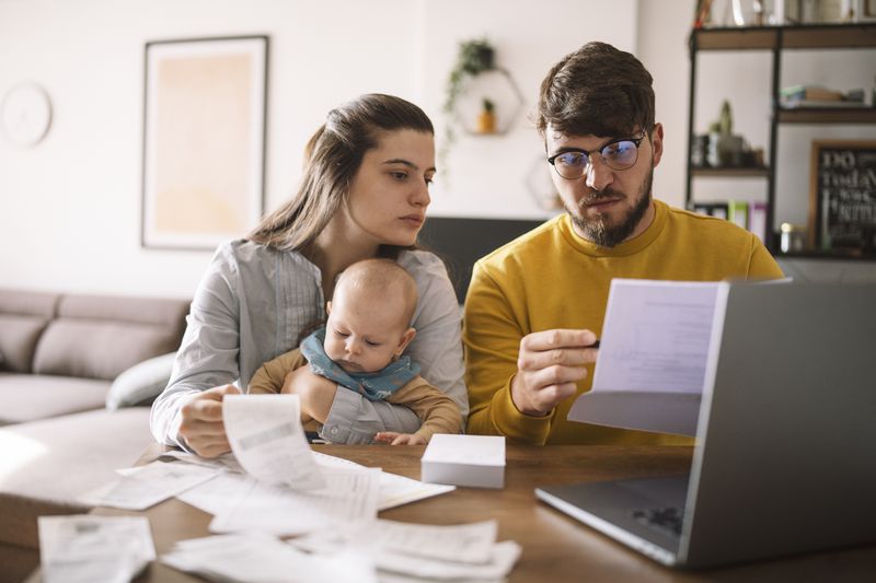 Young couple with baby looking over paperwork.