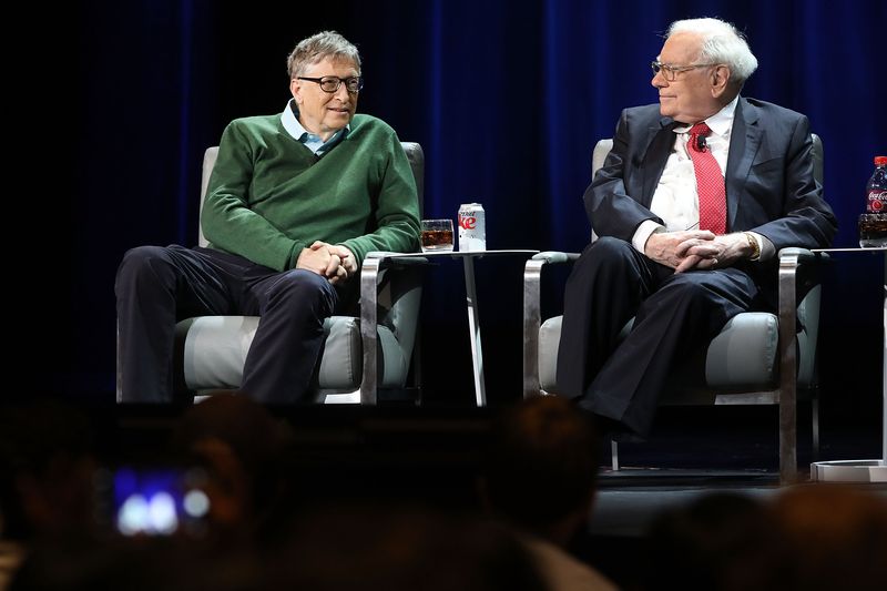 Bill Gates and Warren Buffett sit beside each other on stage, speaking at a Columbia Business School event. 