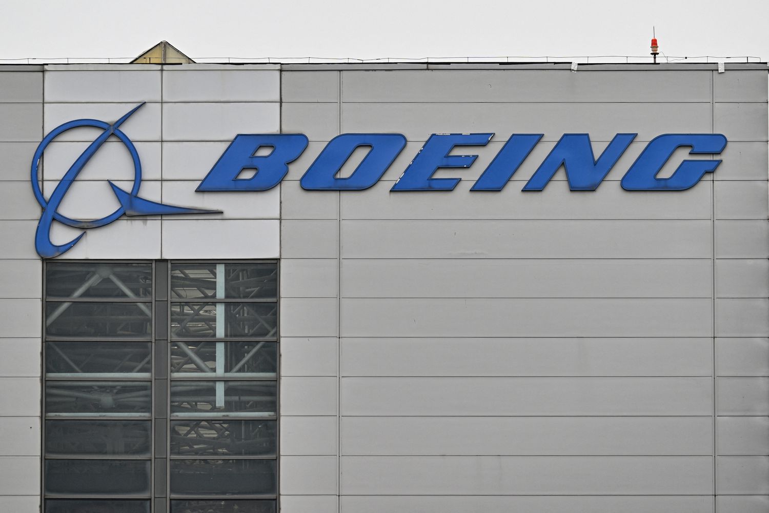 The blue Boeing logo is seen on the side of a gray building.