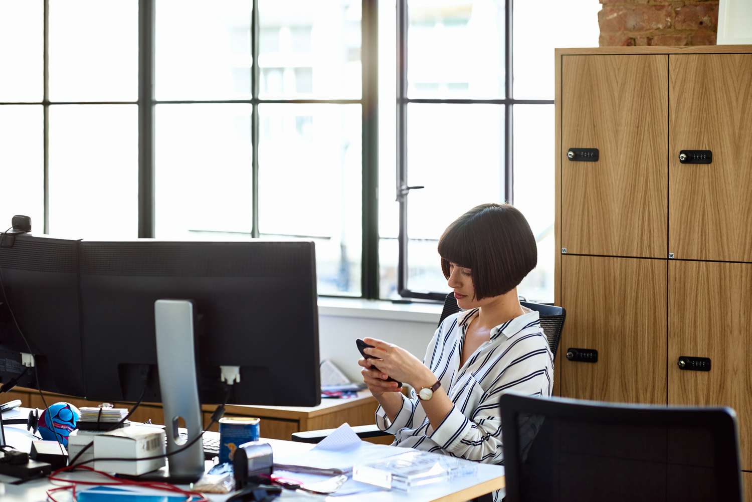 A woman sitting at her desk using a phone. 