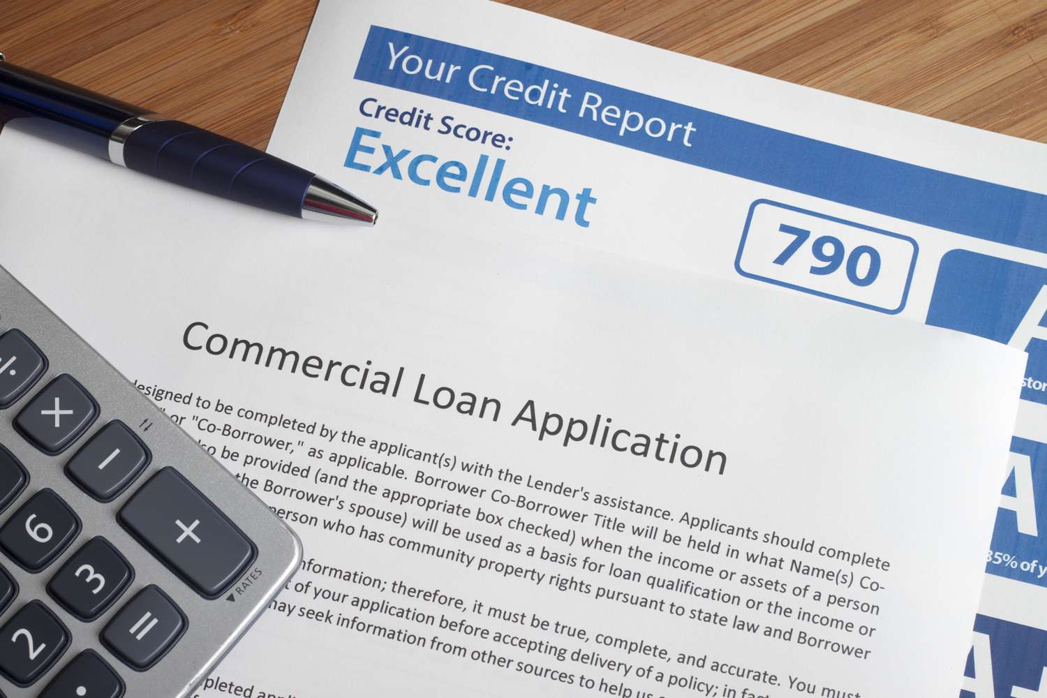 A consumer credit report with excellent score on the table next to a loan application.