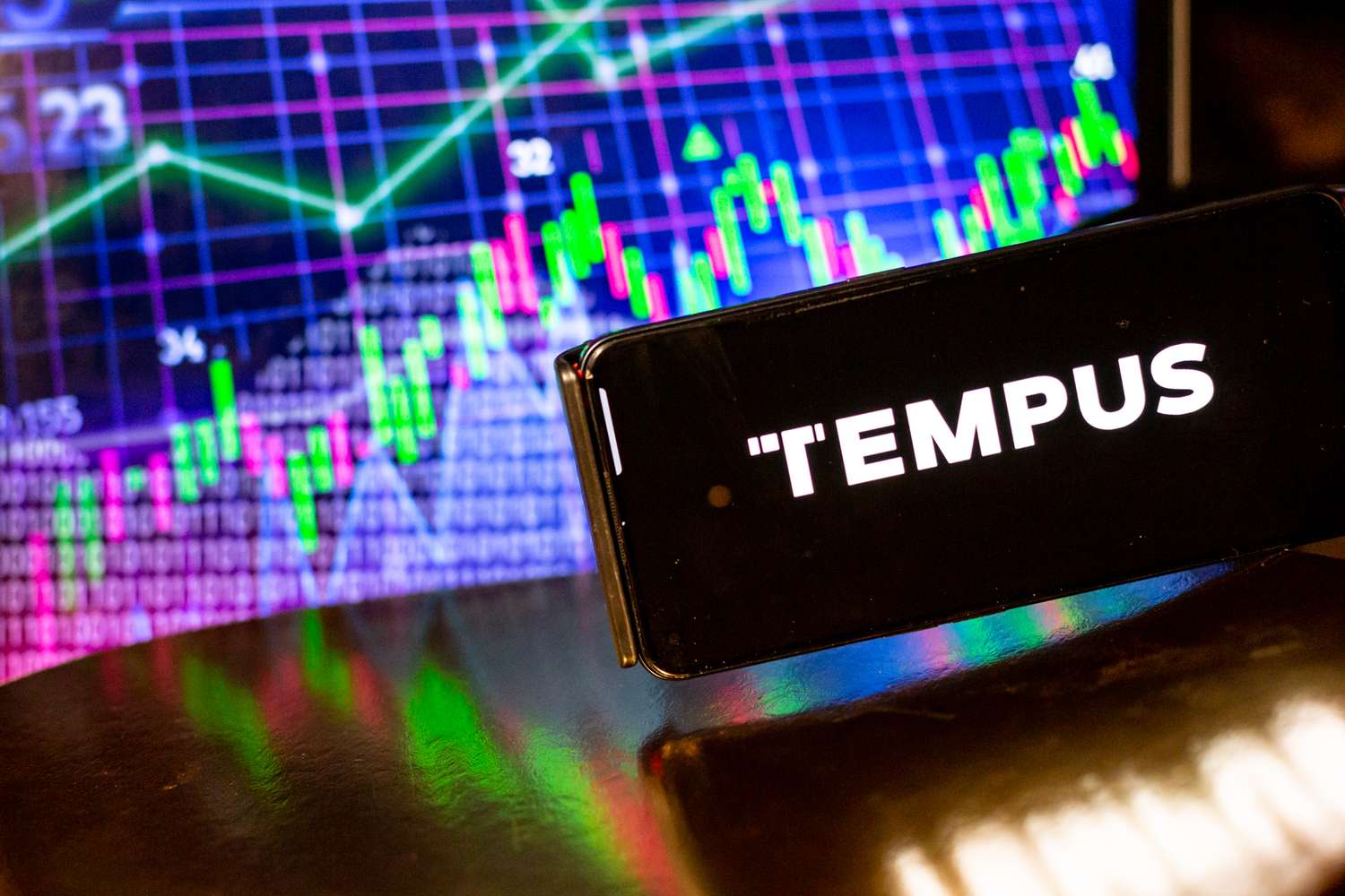 Logo of Tempus AI is seen on a smartphone against a screen displaying a trade markets illustration on April 15, 2024 in Krakow, Poland. 