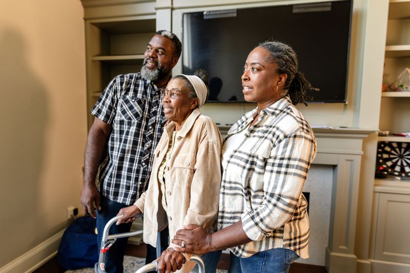 Older woman with a walker surrounded by two family members