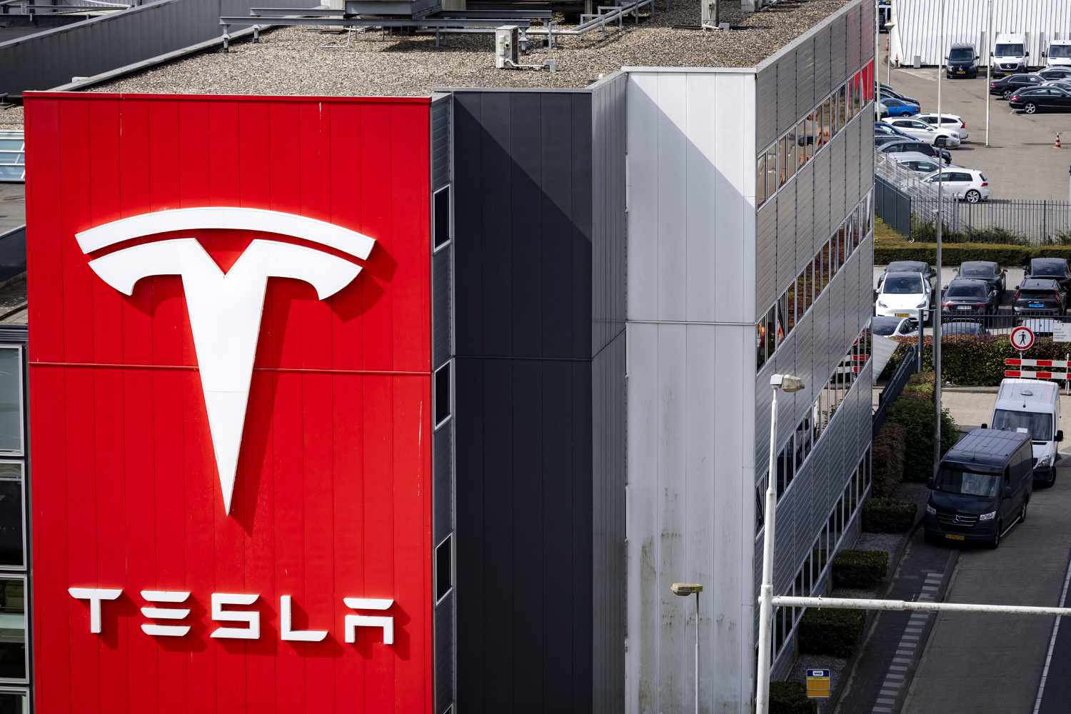 The Tesla logo on the side of a building, with cars in the background