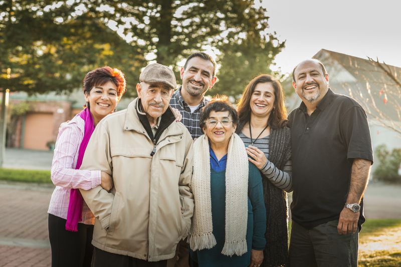 Multi-generation family smiling together outdoors.