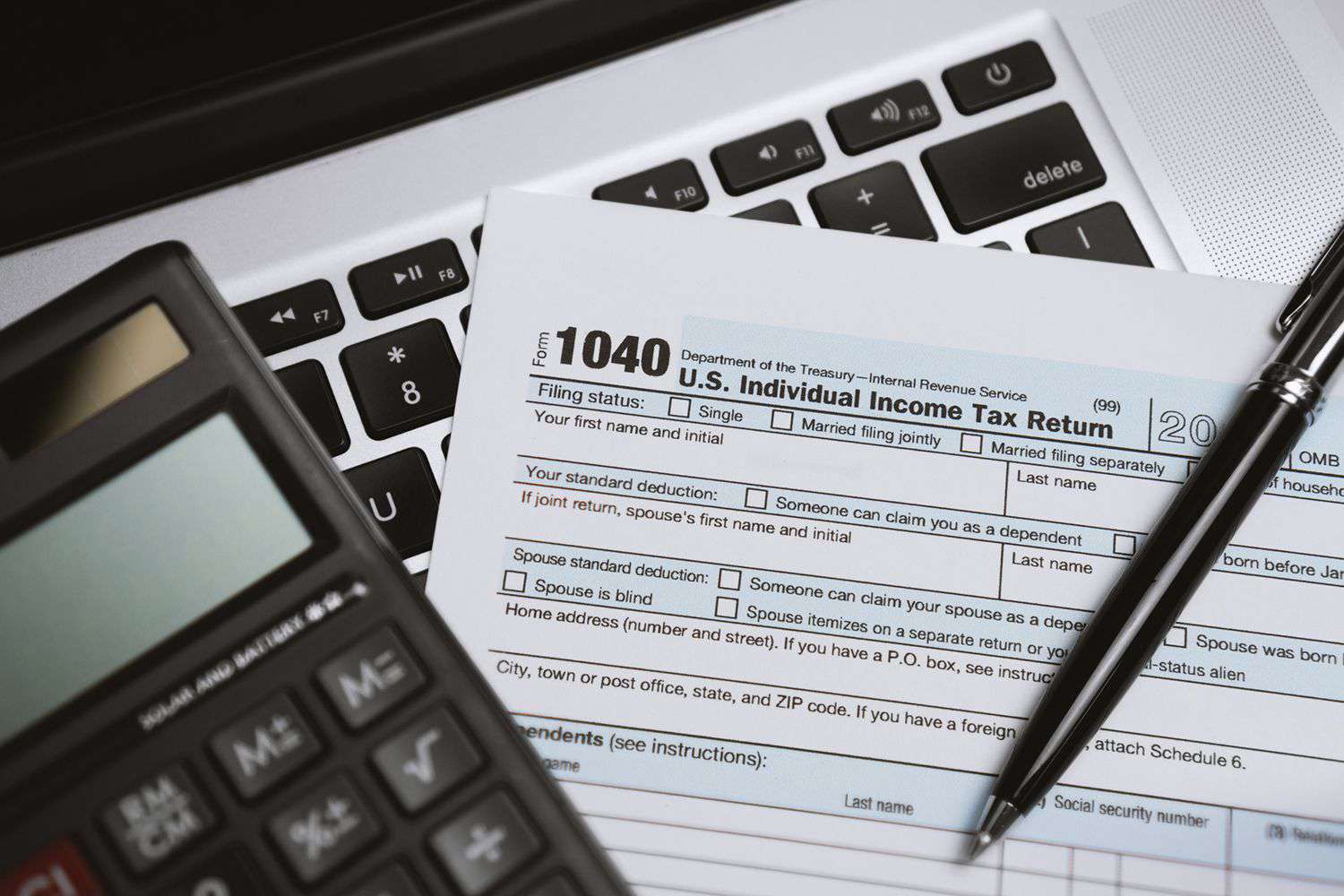 A printed tax form on a laptop with a calculator and a pen