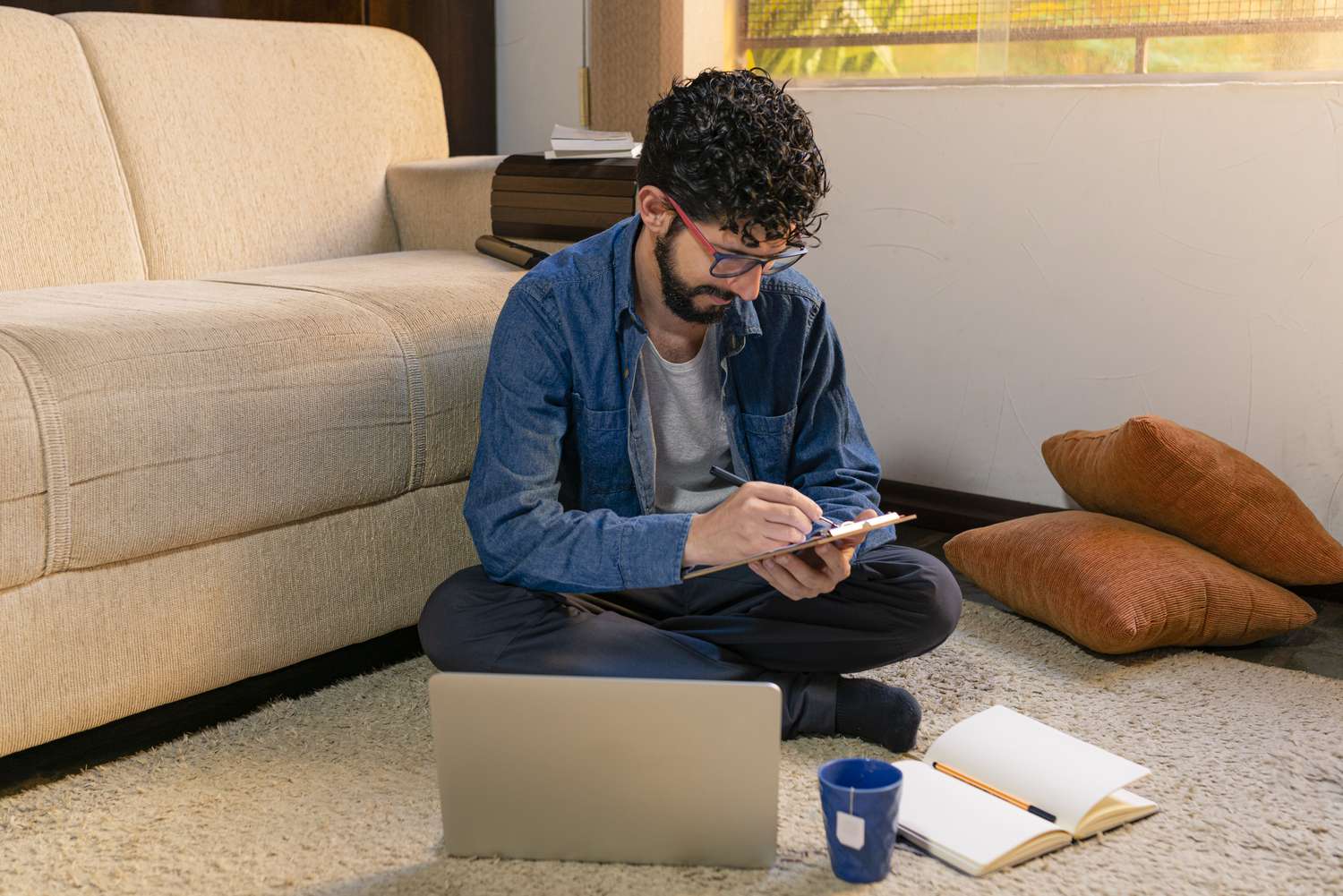 Homeowner sitting on the carpet in the living room and calculating the monthly budget that includes fixed mortgage payment.