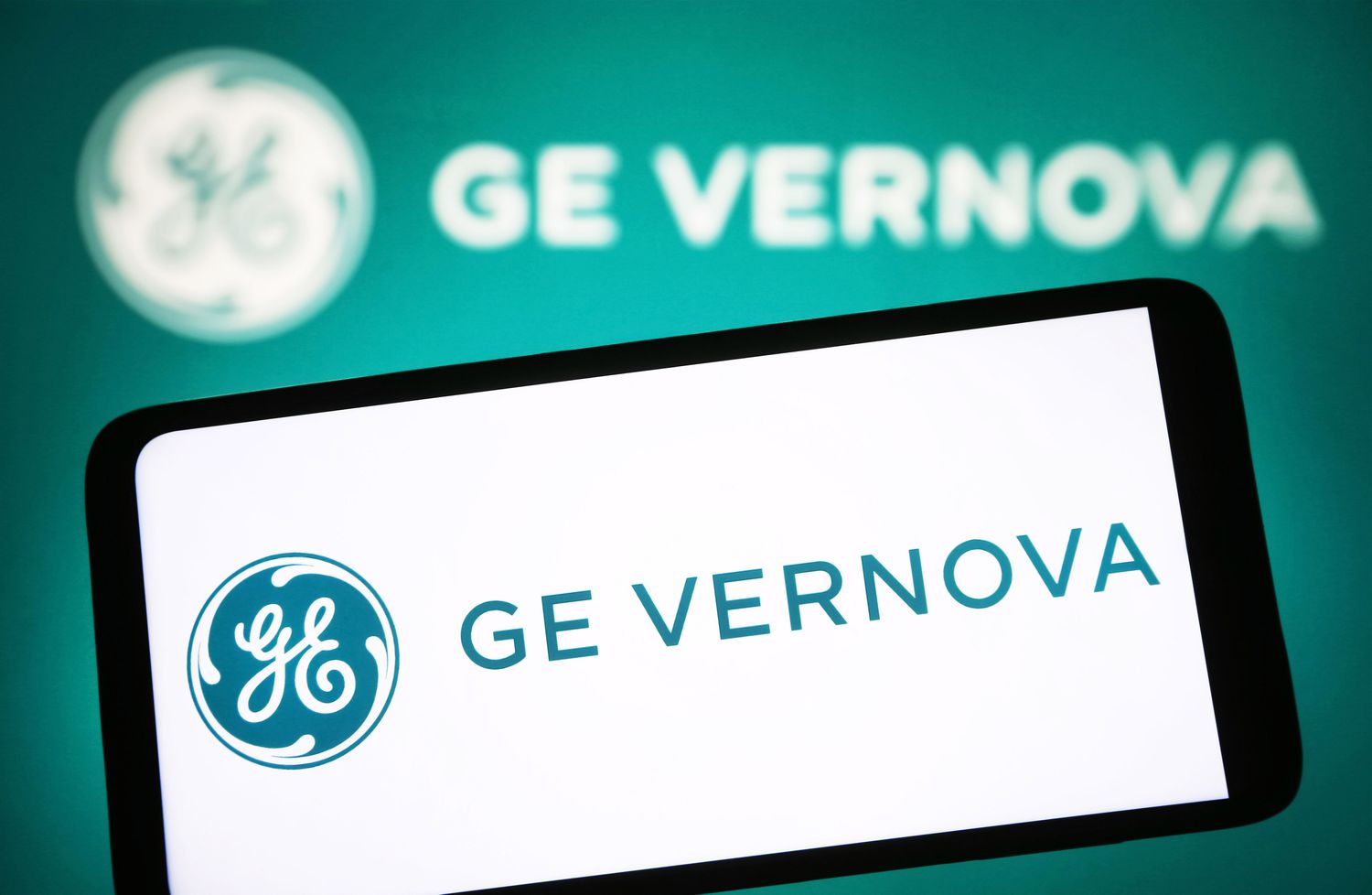The GE Vernova logo is displayed on a phone screen in front of a blue-green background also featuring the GE Vernova logo